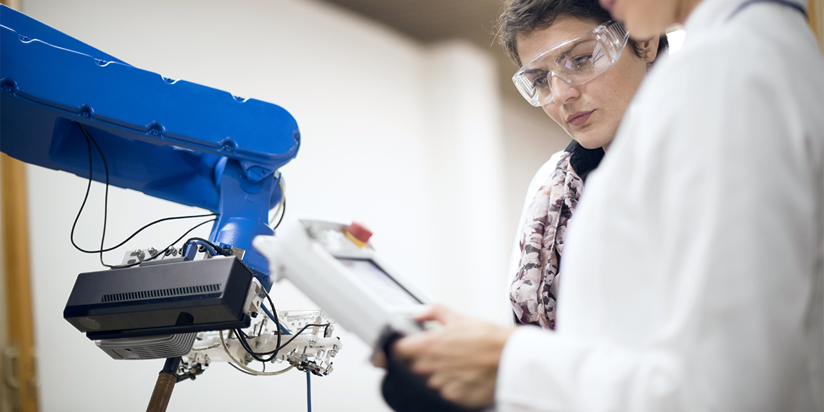 women working in lab with robotic arm