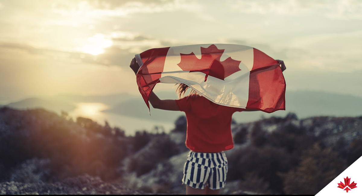 Woman holding Canadian flag in front of mountain landscape