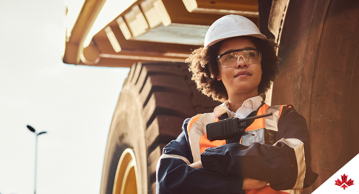 Mine worker standing in front of a large haul dump truck wearing personal protective wear.