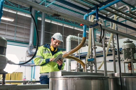 Caucasian technician engineer man in uniform with tablet checking and control boiler tanks and liquid pipeline in chemical factory production line