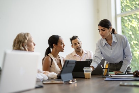 Diverse business professionals working together in a modern office setting with laptops and paperwork