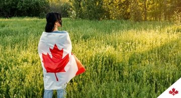 woman wrapped in Canadian flag standing in field