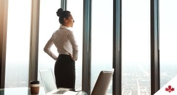 Woman in business attire looking out office window