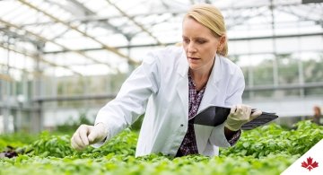 Woman in lab coat in greenhouse