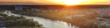 Aerial view of Winnipeg, Manitoba, Canada at sunset with a river running through the city and a bridge in the foreground.