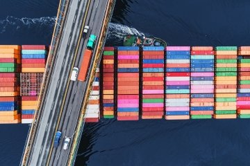 A container ship passes beneath a suspension bridge.
