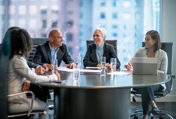 Business team in a boardroom meeting, collaborating around a large table in a modern office setting.