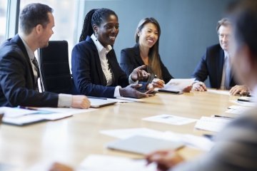 African American professional woman leading business discussion with colleagues in a modern office setting.