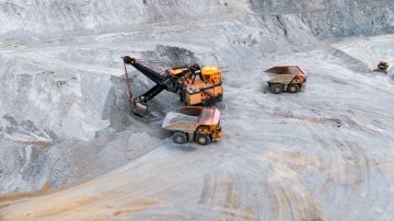 A yellow bulldozer works on a multi‑level open‑pit excavation site surrounded by steep, rocky walls.
