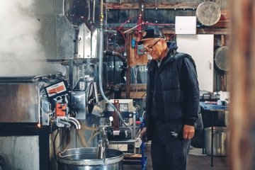 A mature worker testing product in a factory. 