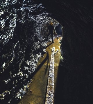 A gold miner is silhouetted in the narrow shaft of a gold mine.
