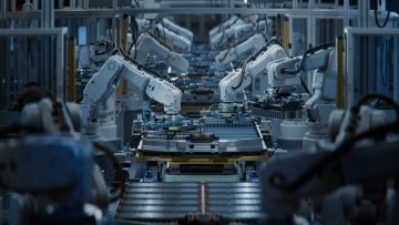 White robotic arms lined up along an automated factory production line assembling electric vehicle battery components.
