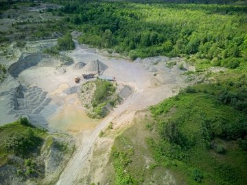 Aerial view of an open pit mine surrounded by green lush trees.