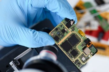 A hand wearing a glove holding a semiconductor.