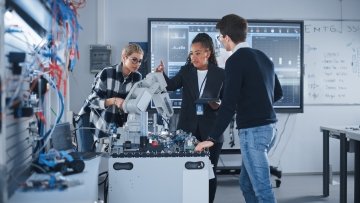 Teacher and students working together in a robotics laboratory with electronic equipment.