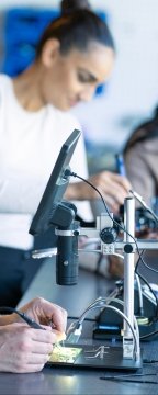Close-up of hands working on electronic circuit boards and components.