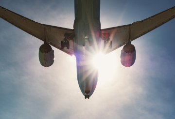 A passenger jet is back lit by the afternoon Sun while preparing for landing.