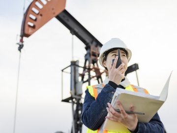Female Oil Worker working at oil field with talkie, Saskatchewan, Canada.